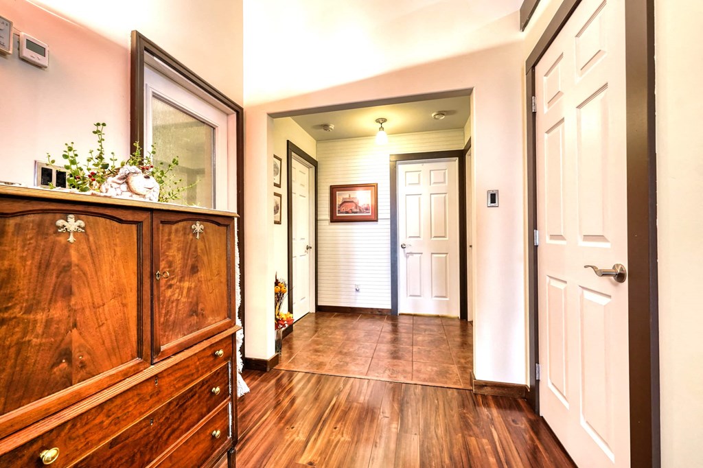 a hallway with wooden floors and white doors and a dresser