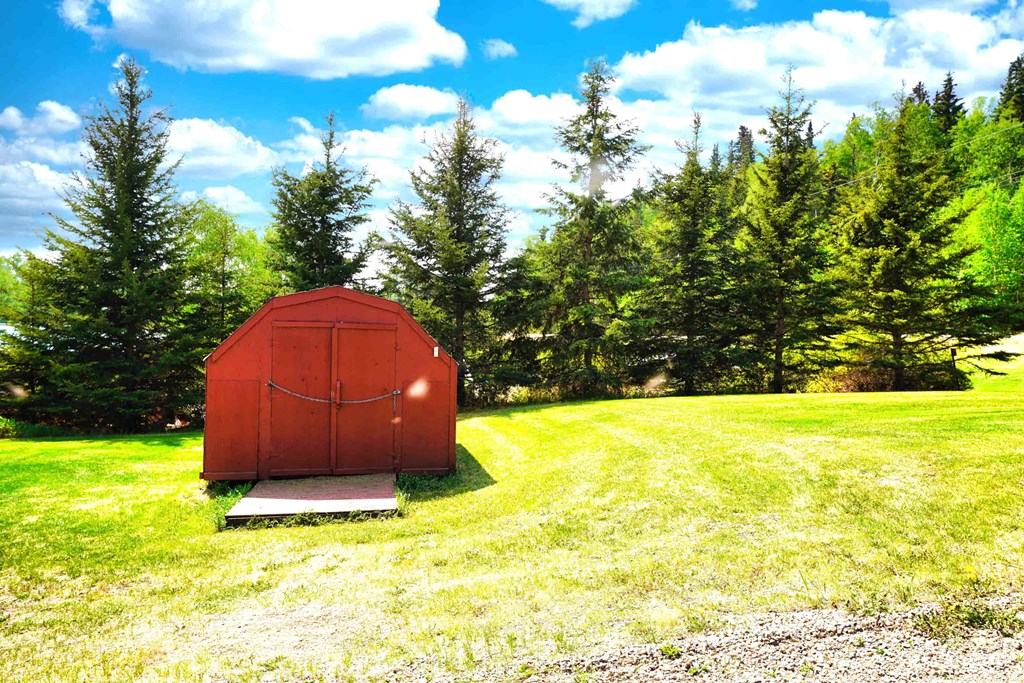 a small red covered shed in the middle of a field