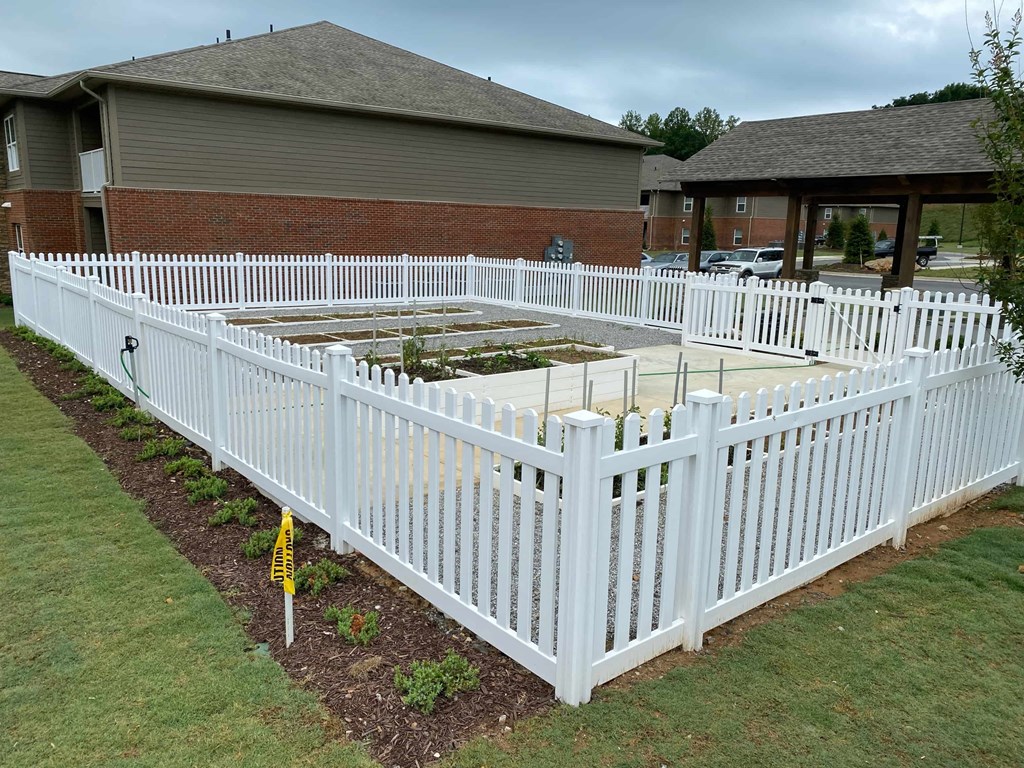 a white fence around a garden in front of a house