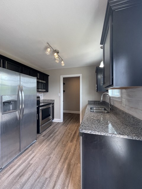 A kitchen with a granite counter and stainless steel appliances.