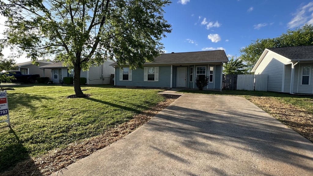 a white house with a driveway and a tree