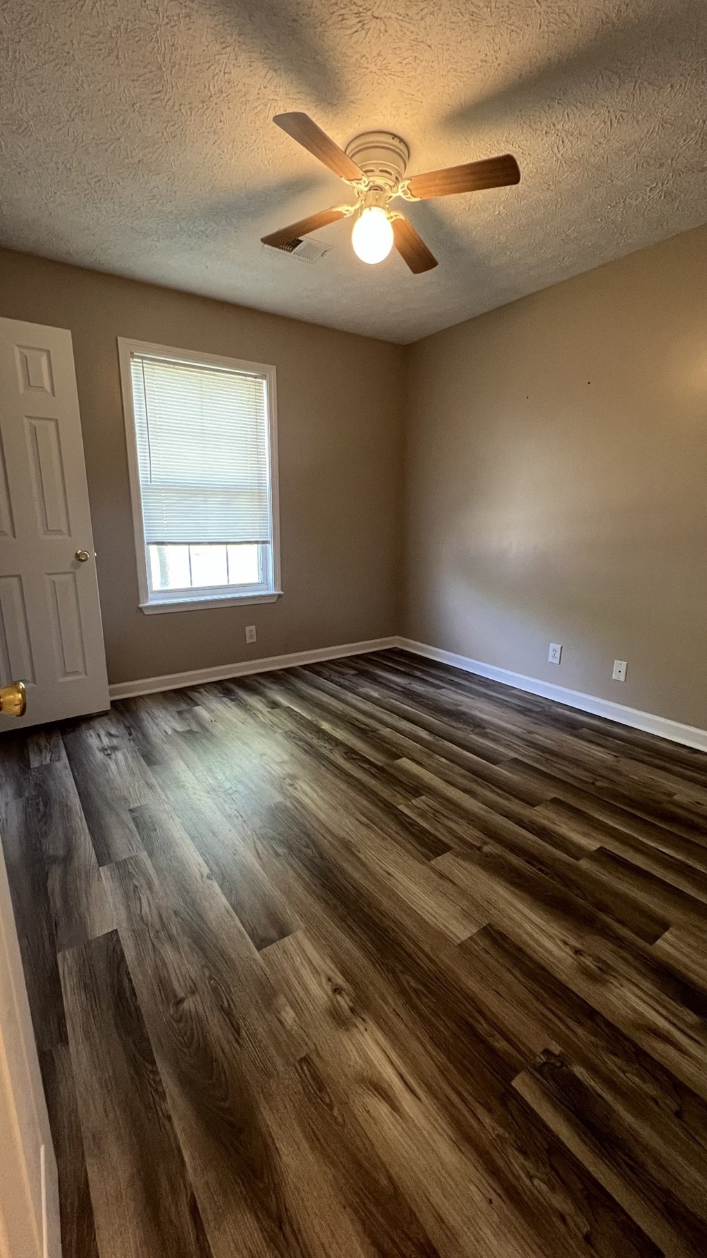 an empty living room with wooden floors and a ceiling fan