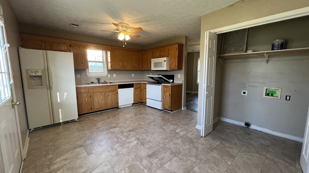 an empty kitchen with white appliances and wooden cabinets
