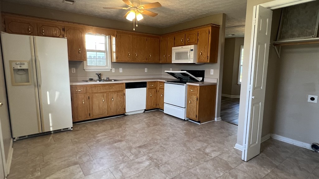 an empty kitchen with white appliances and wooden cabinets