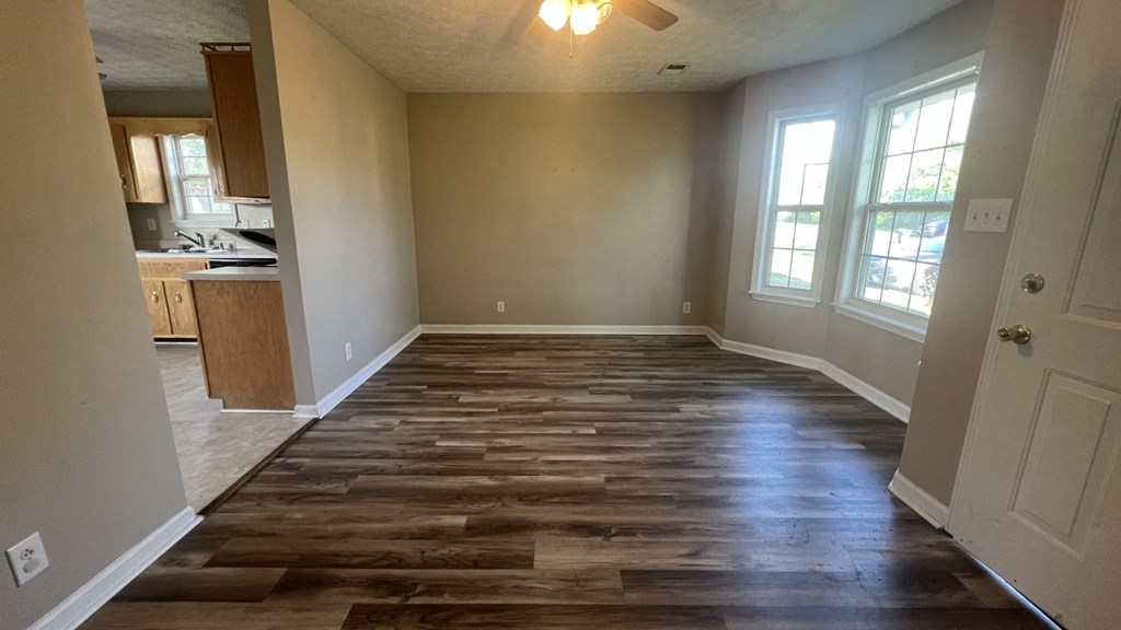 an empty living room with wooden floors and a kitchen