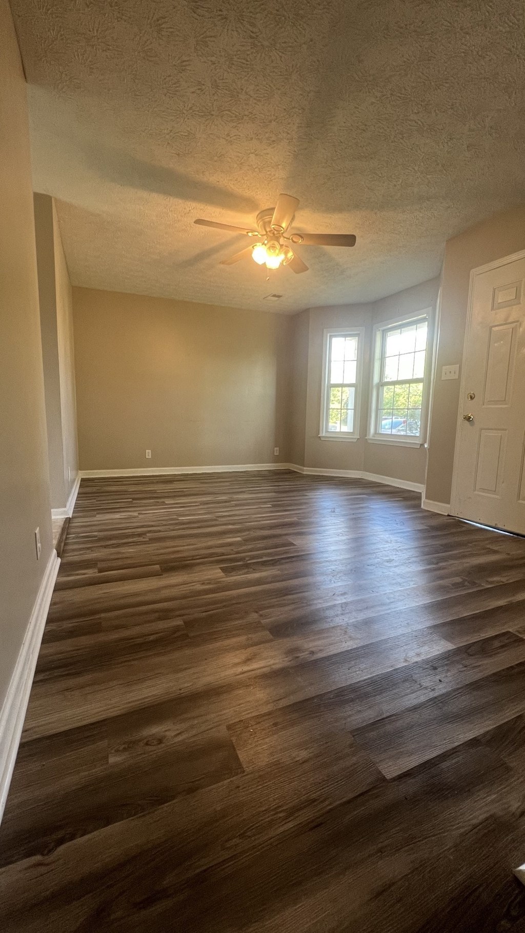 an empty living room with wooden floors and a ceiling fan