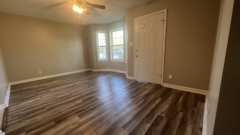 an empty living room with wooden floors and a white door
