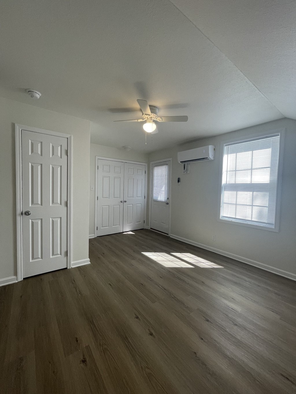 an empty living room with white walls and a ceiling fan