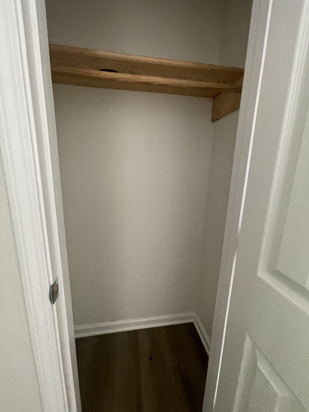 a small room with a wooden shelf on the wall and a door
