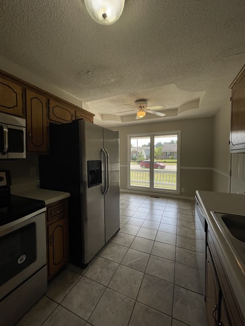 A kitchen with a refrigerator, microwave, and oven.