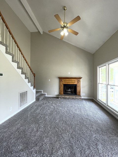 A living room with a fireplace and a ceiling fan.