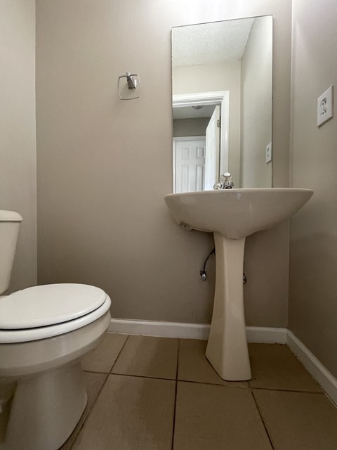 A white toilet sits next to a pedestal sink in a bathroom.