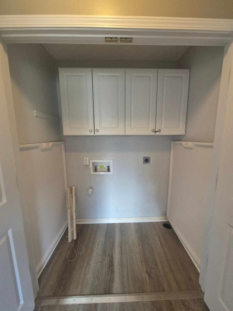 A kitchen with white cabinets and wood flooring.