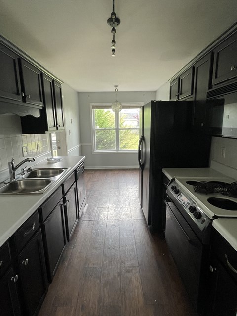 an empty kitchen with black cabinets and stainless steel appliances