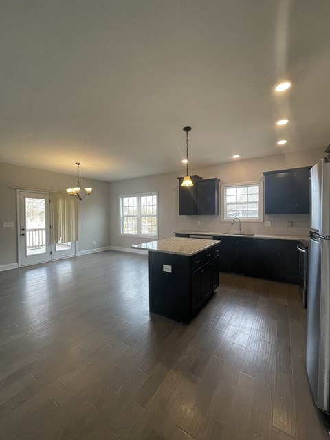 A kitchen with black cabinets and a wooden floor.