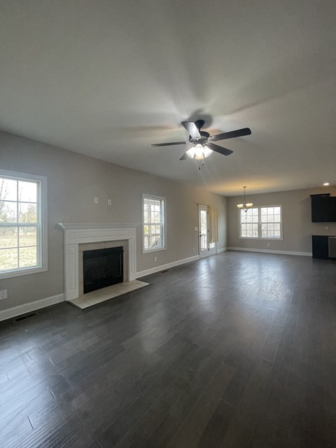 A spacious room with a fireplace and a ceiling fan.