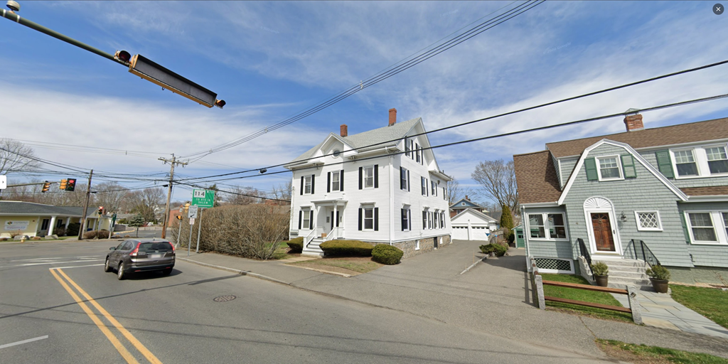 a white house on the corner of a street with a car