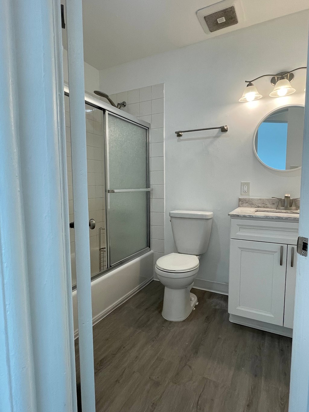 A white toilet sits in a bathroom next to a shower.