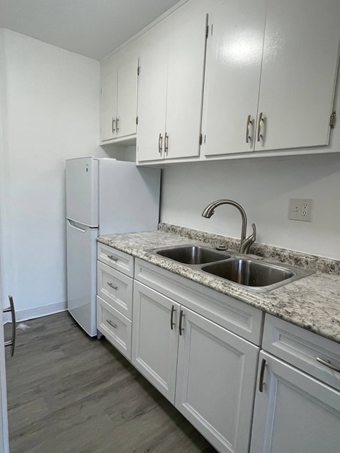 A kitchen with white cabinets and a granite countertop.
