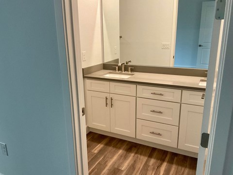 a bathroom with white cabinets and a sink and a mirror