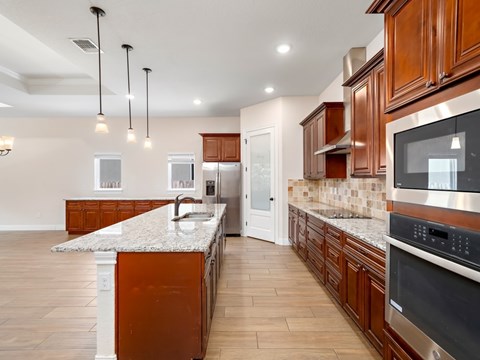 a large kitchen with wooden cabinets and marble counter tops