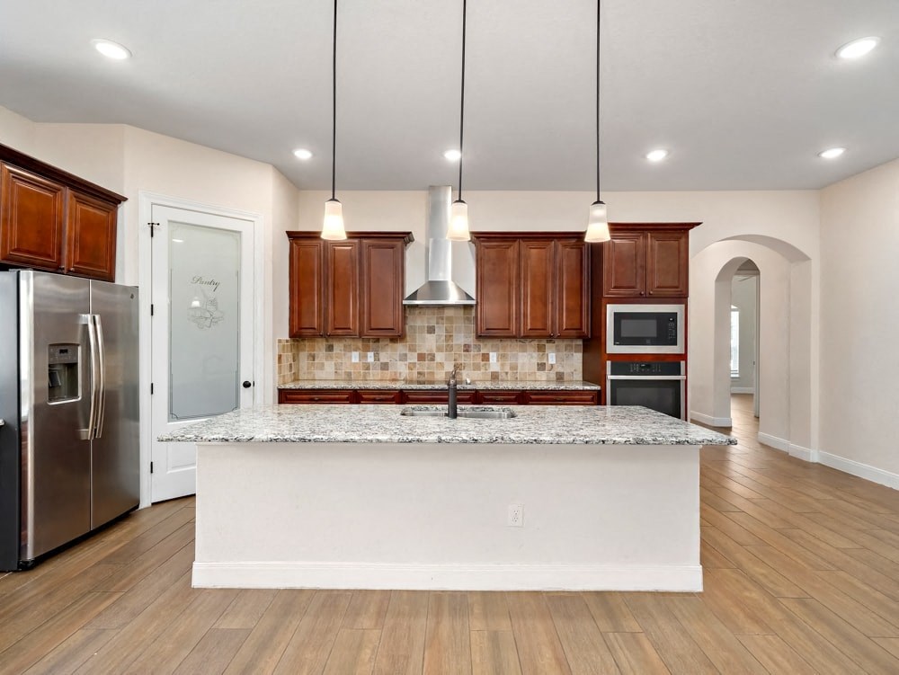 a kitchen with a large island and a stainless steel refrigerator