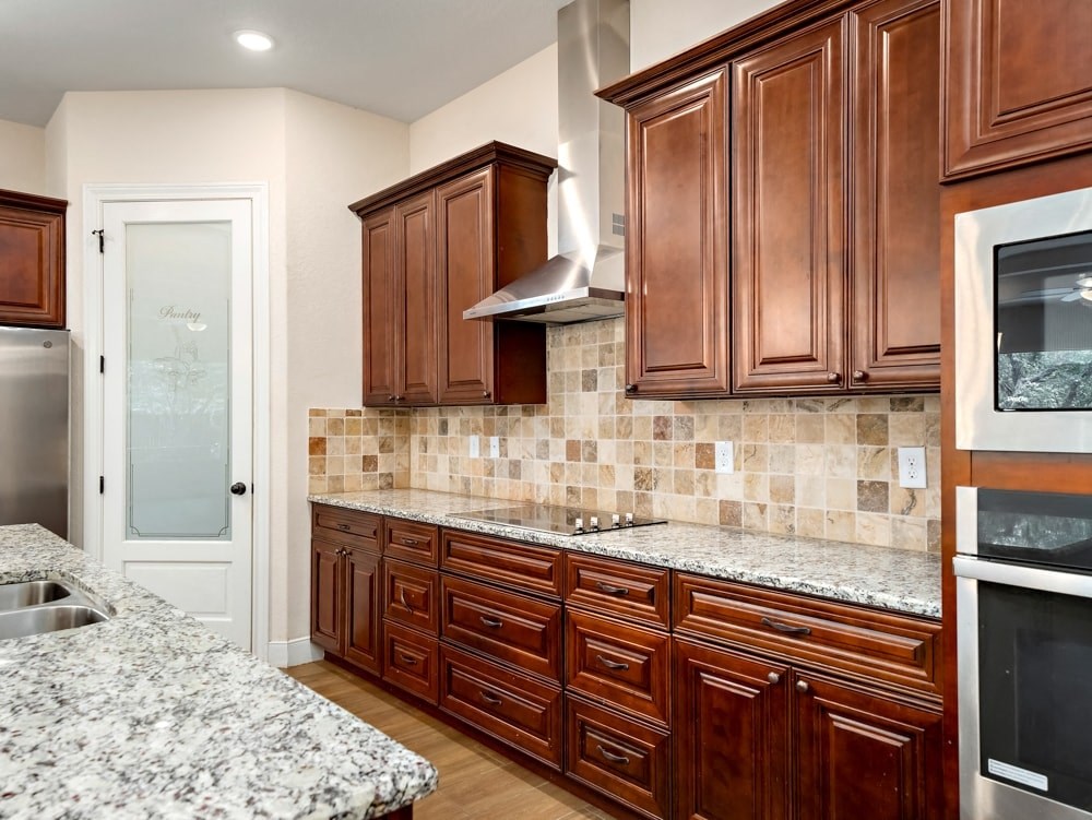 a kitchen with wooden cabinets and marble counter tops
