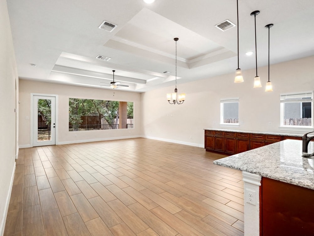 an open kitchen and living room with hardwood floors and a large window
