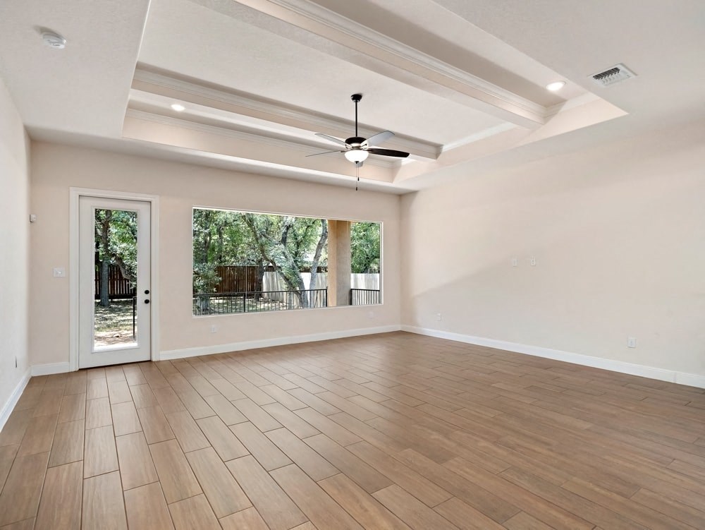 an empty living room with wood floors and a ceiling fan