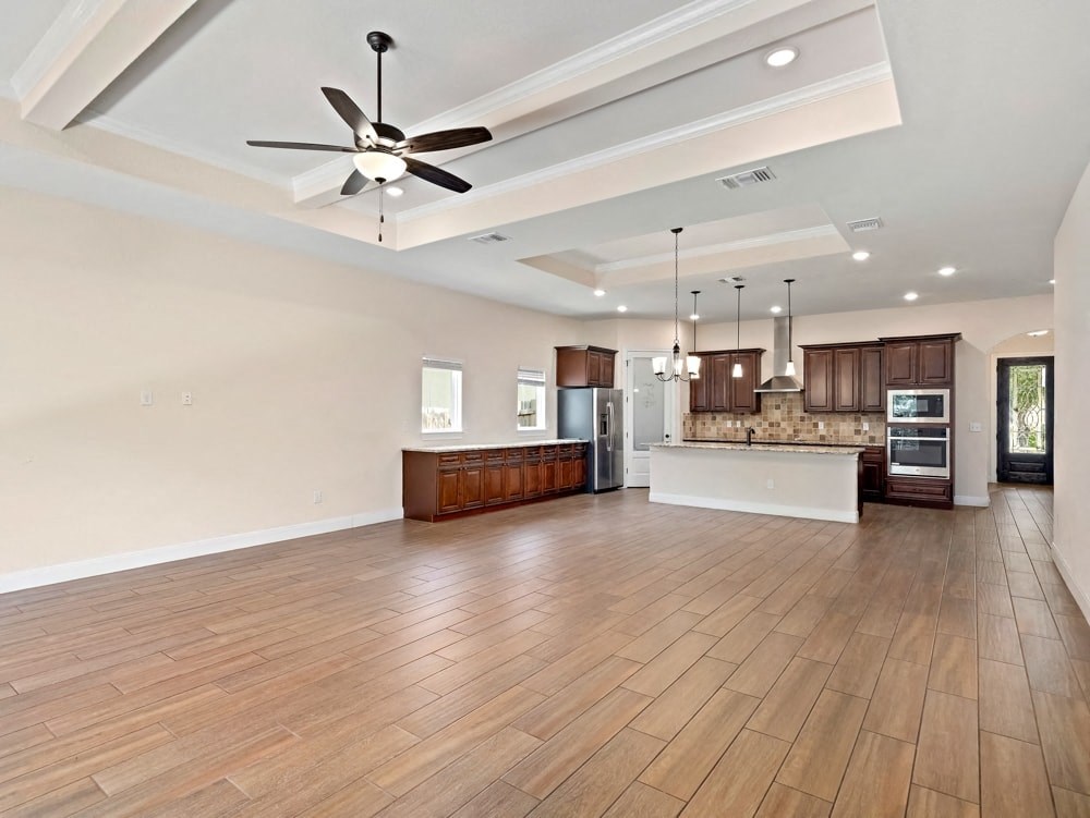an open kitchen and living room with wood floors and a ceiling fan