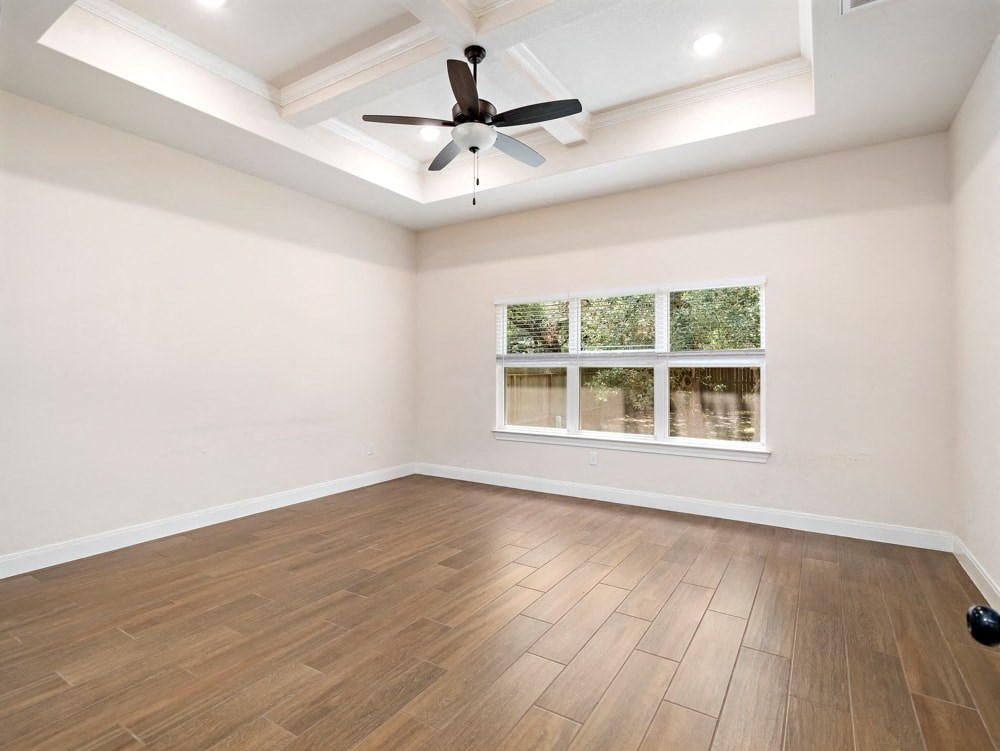 an empty living room with a ceiling fan and a window