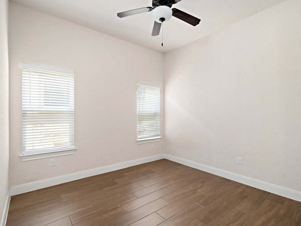 an empty room with wood flooring and a ceiling fan