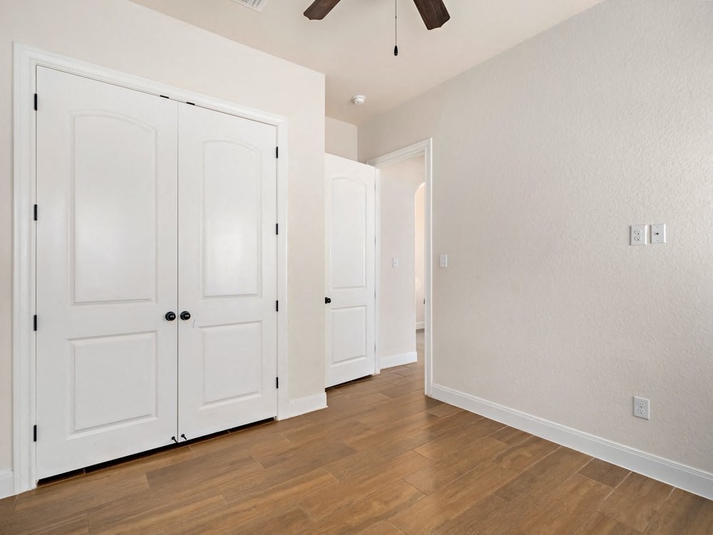 a renovated living room with white doors and a ceiling fan