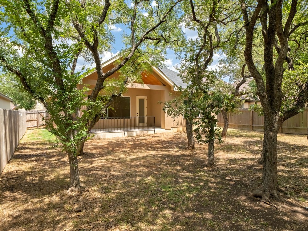 a backyard with trees and a house in the background