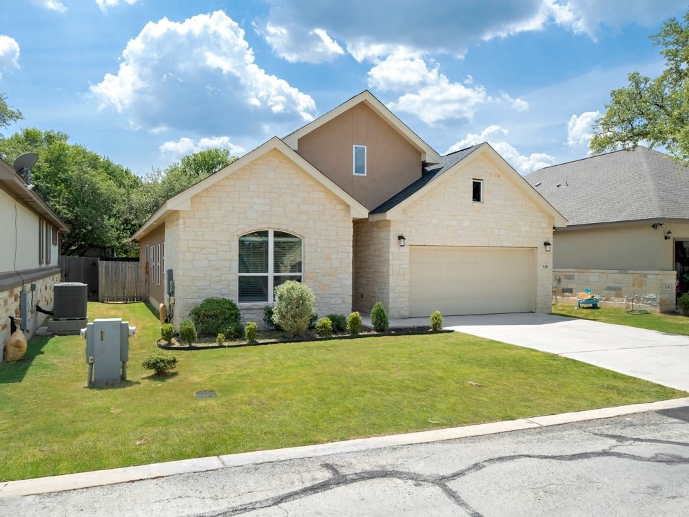 a beige brick house with a lawn and a driveway