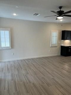 an empty living room with a ceiling fan and wood floors