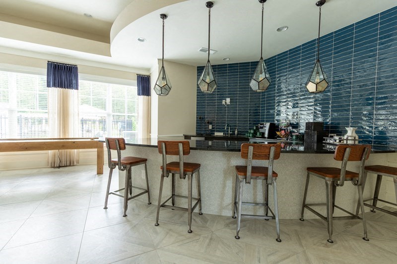 a large kitchen with bar stools and blue tiles