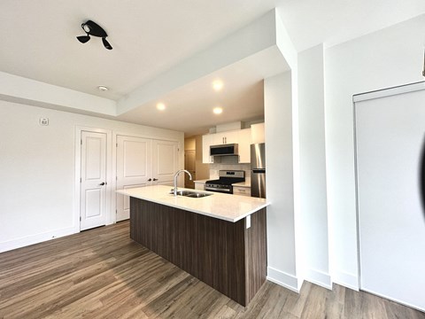A kitchen with a white counter top and wooden flooring.