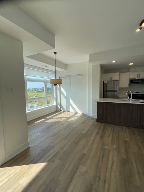 A modern kitchen with wooden floors and a large window.