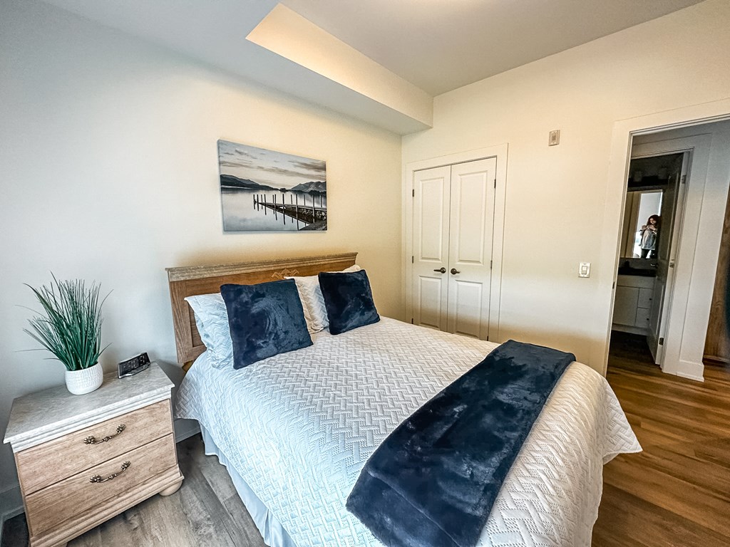 A bedroom with a bed, dresser, and painting on the wall.