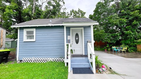 A small blue house with a white door and a white picket fence.
