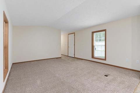the living room and dining room of a house with carpet and a window