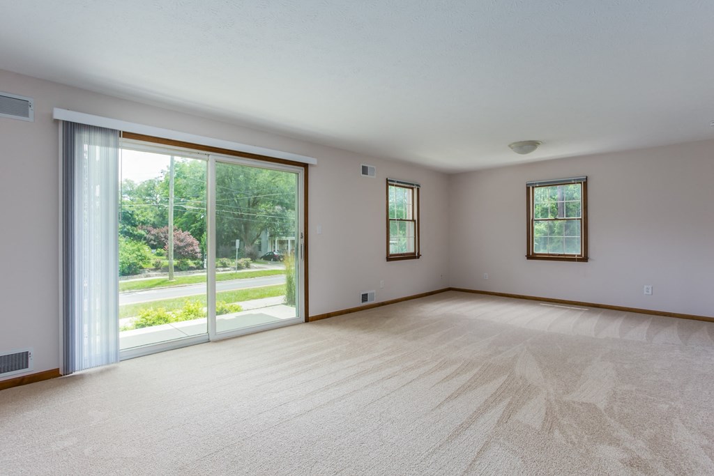 an empty living room with a large window and a door to the yard