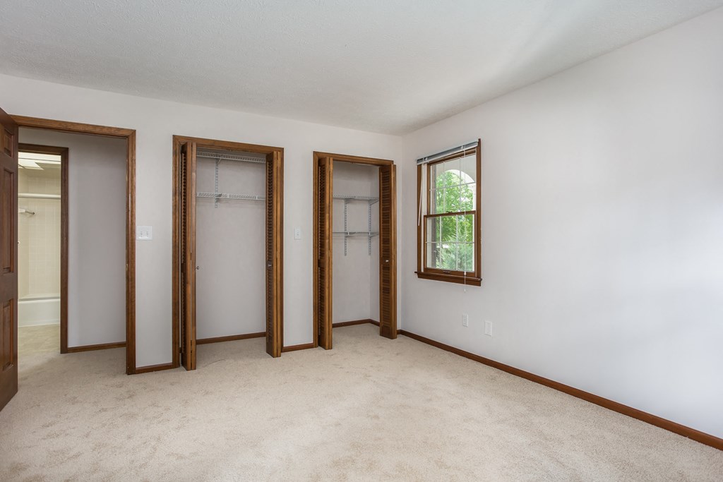 a bedroom with three doors and a carpet floor and white walls