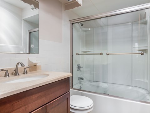 A modern bathroom with a glass shower stall and a white toilet.