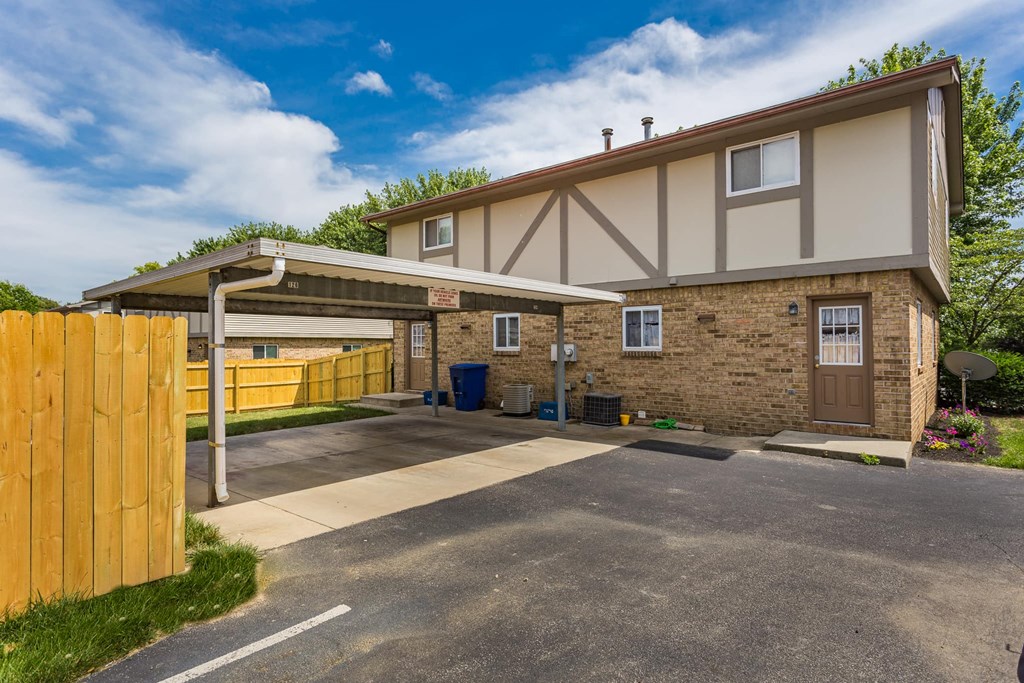 the front of a house with a parking lot and a wooden fence
