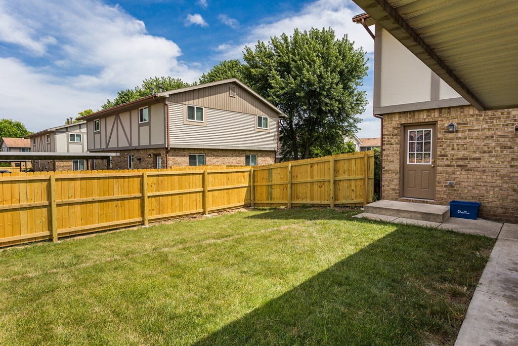 a wooden fence in front of a yard with a house