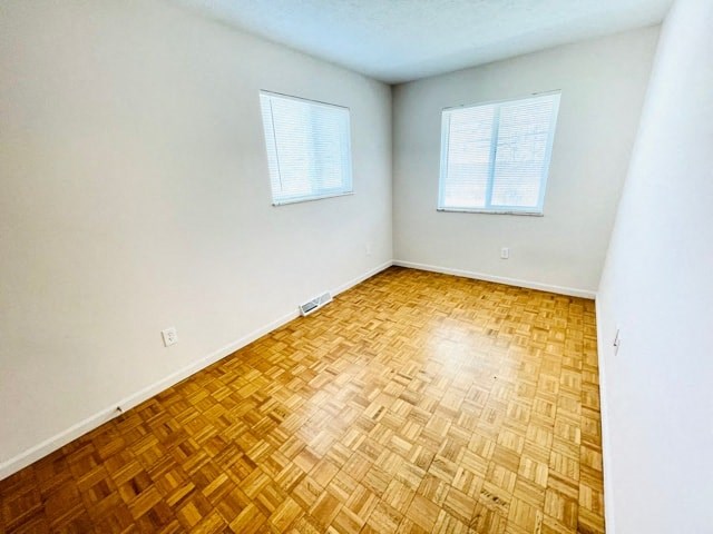 an empty room with a wooden floor and two windows
