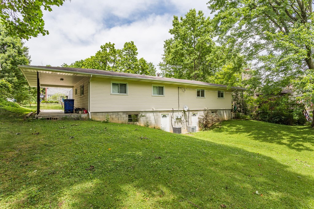 the front of a house with a green lawn and trees