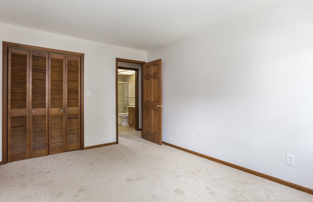a bedroom with a closet and a door to a bathroom